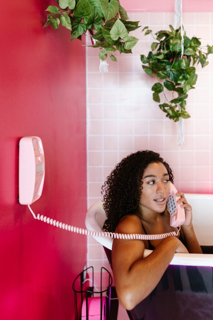 Woman Talking on the Phone while Sitting in a Bathtub