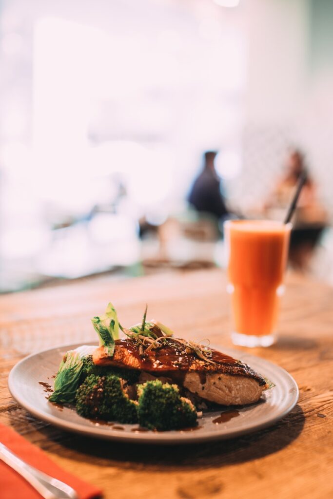Salmon and Broccoli Dish on Table and Carrot Juice in Background