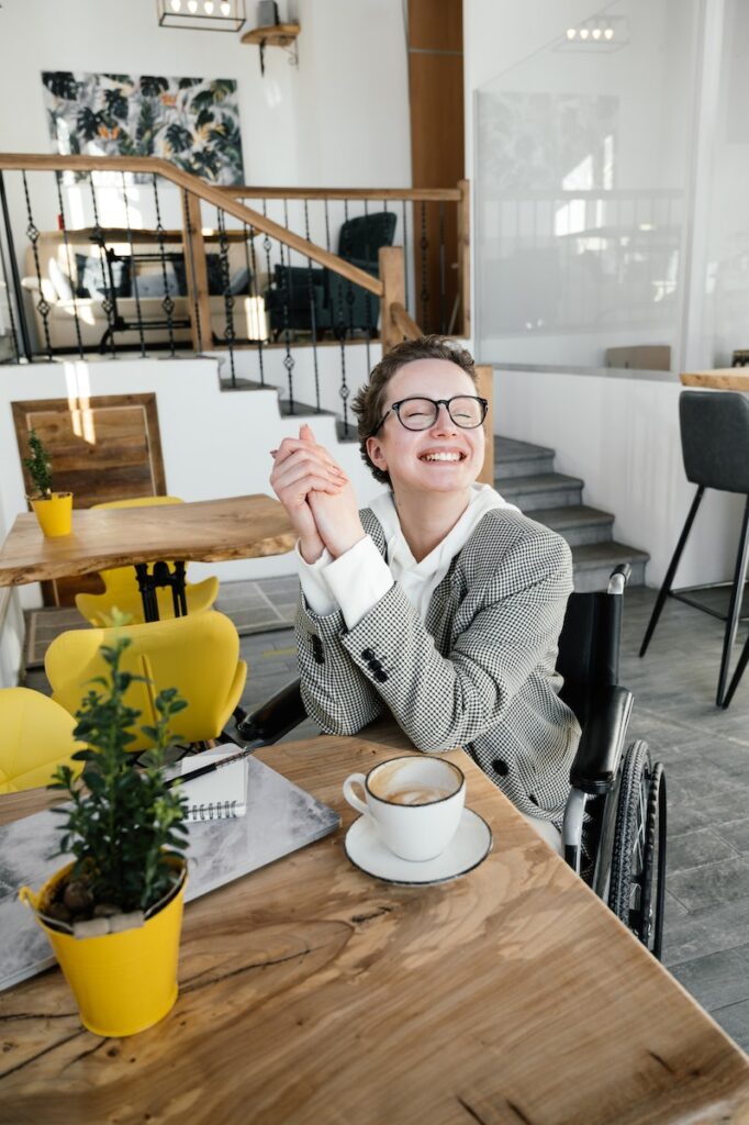 Satisfied woman in wheelchair having latte in coffee shop
