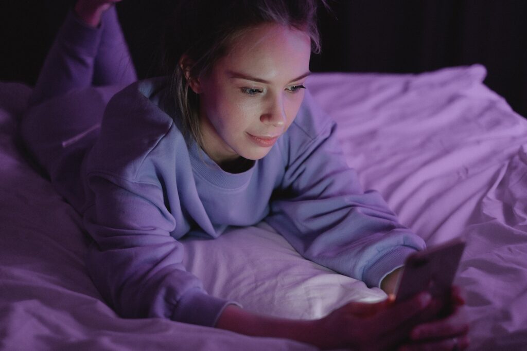Woman Lying on Bed while Using a Cellphone