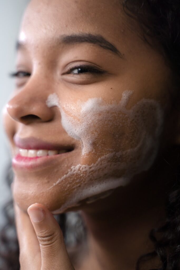 Close-Up Shot of a Curly-Haired Woman Cleaning Her Face As part of her skincare routine