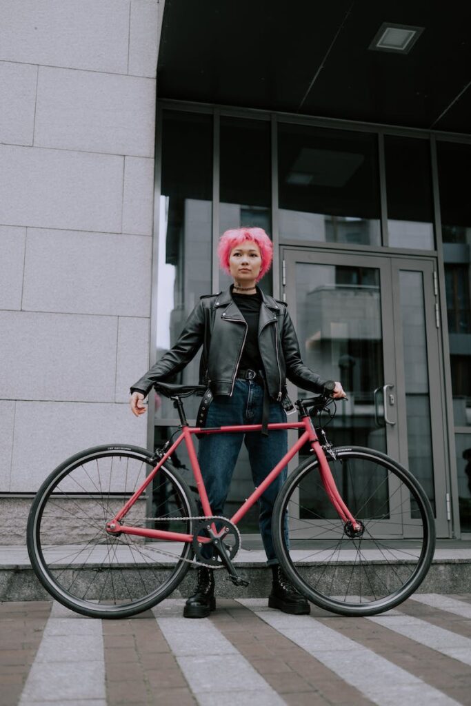 A Woman in Black Leather Jacket is Standing Beside a Bicycle